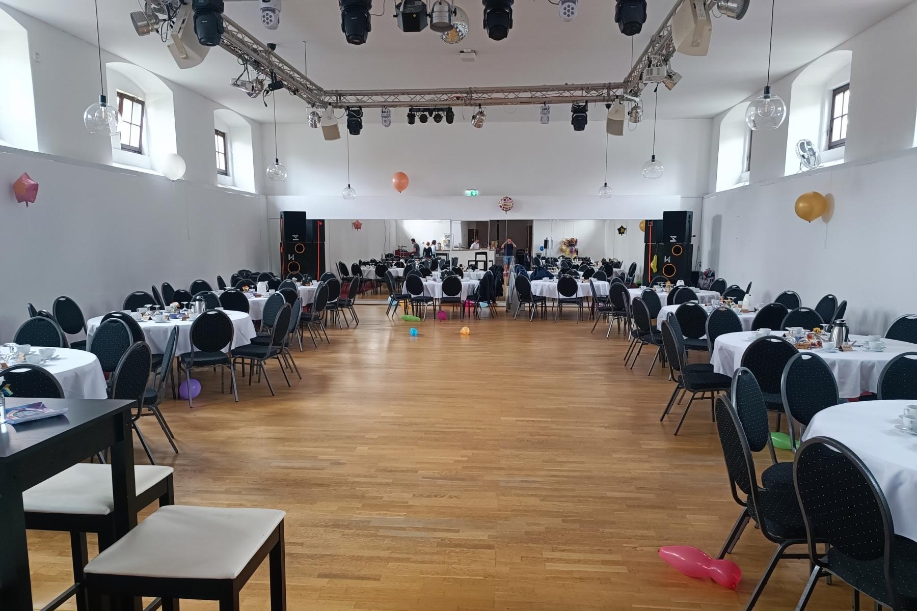 Festlich geschmückter Hochzeitssaal mit eleganter Dekoration und moderner Bar im historischen Marstall Gotha. Der Raum ist beleuchtet und bietet einen festlichen Rahmen für Hochzeitsfeiern und Events in Thüringen