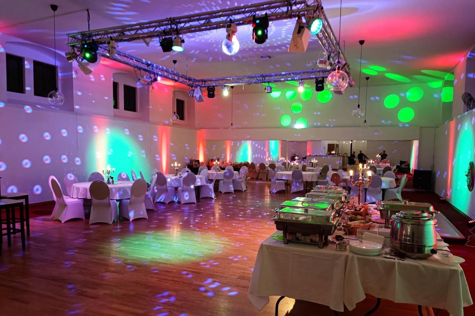 Großzügiger Partyraum im Marstall Gotha mit stilvoll arrangiertem Buffet, runden Tischen und eleganten weißen Hussen. Der Raum bietet eine gemütliche Atmosphäre für Hochzeitsfeiern mit ausreichend Platz für Gäste, kulinarische Highlights und ausgelassene Partys.